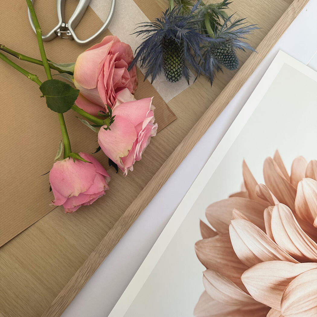Pretty, fresh cut flowers on a studio table next to a photograph ready for framing.